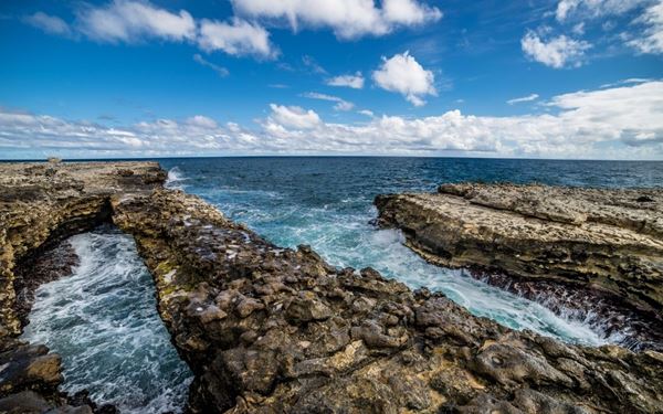 Devil's Bridge is a dramatic natural limestone arch carved over centuries by the powerful waves of the Atlantic Ocean. Located on the rugged eastern coast, the site features natural blowholes that shoot sea spray high into the air. It is a place of raw natural beauty and historical significance, as local folklore connects the site to the island's past, offering a wild and picturesque coastal experience.