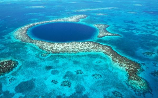 The Great Blue Hole is a massive underwater sinkhole off the coast of Belize and a world-class destination for scuba divers. Surrounded by the Lighthouse Reef, its deep blue waters are home to impressive stalactites and diverse marine life, including several species of sharks. This natural wonder is a UNESCO World Heritage site and offers an unforgettable experience for ocean adventurers.