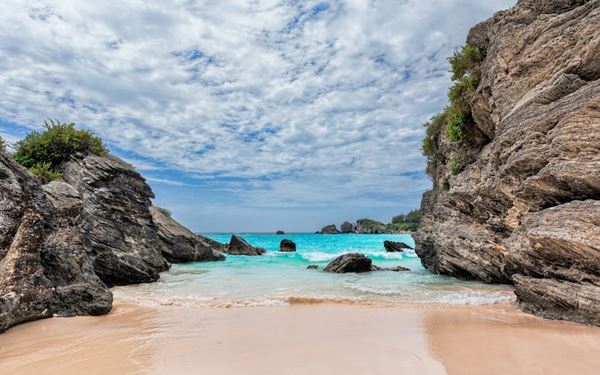 Horseshoe Bay is Bermuda's most famous beach, renowned for its characteristic pale pink sand and translucent turquoise waters. Curved in a dramatic crescent shape, it is flanked by impressive limestone rock formations that provide natural caves to explore. It is a premier spot for swimming, snorkeling, and enjoying the unique island beauty that defines Bermuda.