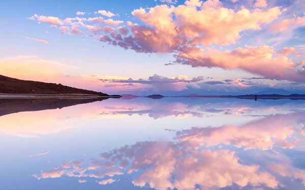 Salar de Uyuni is the world’s largest salt flat, covering over 10,000 square kilometers. During the rainy season, a thin layer of water transforms it into the world's largest natural mirror, creating a surreal reflection of the sky. This otherworldly landscape, filled with octagonal salt patterns and cactus-covered islands, offers one of the most unique photographic opportunities on Earth.