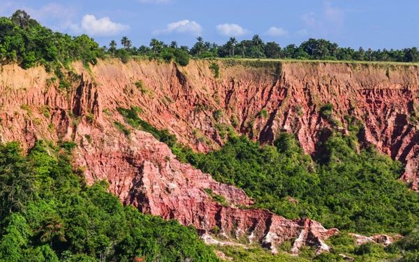 Known as the "Grand Canyon of the Congo," the Diosso Gorges feature dramatic red rock cliffs and lush green canopies that plunge into the Atlantic coast. The erosion has created stunning ridges and spires that change color with the sunlight. It is a place of immense natural beauty and local legends, offering a spectacular landscape that contrasts the dense jungle with the rugged coastal geography.
