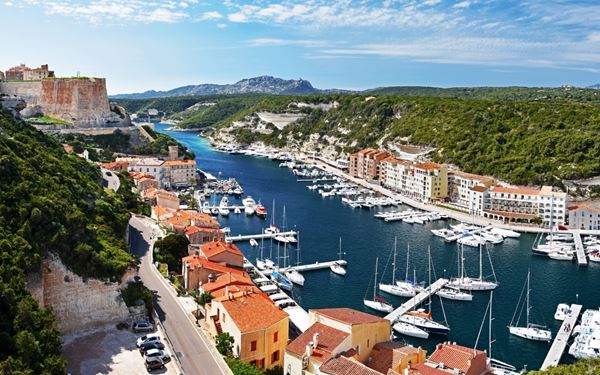 Perched on a high limestone cliff, the medieval Citadel of Bonifacio overlooks the sparkling Strait of Bonifacio towards Sardinia. Its narrow streets and ancient walls seem to hang precariously over the sea. Walking through the old town and descending the King of Aragon Steps offers a thrilling journey into history, set against a backdrop of majestic coastal views and luxury yachts in the harbor.