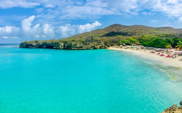 Kenepa Grandi is often considered the most beautiful beach in Curacao, featuring a stunning crescent of white sand and some of the clearest turquoise water in the Caribbean. Surrounded by lush green hills, it is a favorite for snorkeling and cliff jumping. The beach offers a quintessential tropical escape with a relaxed local vibe, showcasing the incredible natural coastal beauty of the island's Westpunt region.