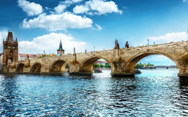 Charles Bridge is a historic 14th-century stone bridge crossing the Vltava River, famous for its 30 statues of saints. Walking across the bridge provides breathtaking views of Prague Castle and the river. It is a lively spot filled with artists and musicians, serving as a vital link between the Old Town and the Lesser Town (Malá Strana).