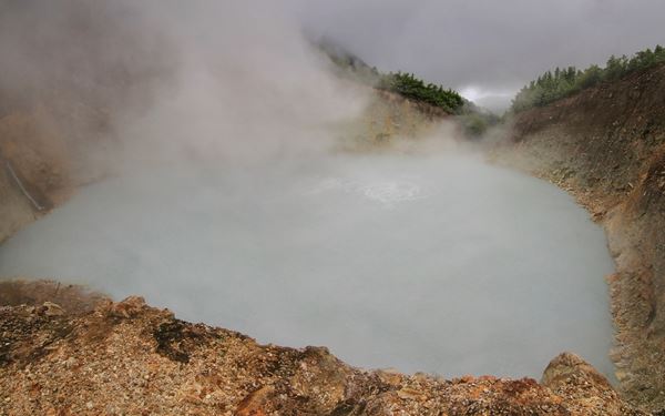 Boiling Lake in Morne Trois Pitons National Park is the second-largest flooded fumarole in the world. The hike to the lake is a challenging adventure through the "Valley of Desolation," featuring volcanic vents and hot springs. The sight of the gray-blue water shrouded in thick clouds of steam is a powerful display of the island's raw geothermal energy.
