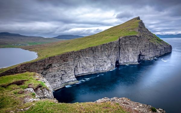 Sørvágsvatn is the largest lake in the Faroe Islands, famous for the optical illusion that it sits high above the ocean. A hike to the Trælanípa cliff offers a perspective where the lake appears to float over the crashing waves of the sea. This unique geological formation, combined with the rugged coastal cliffs, creates one of the most surreal and photographed landscapes in the world.