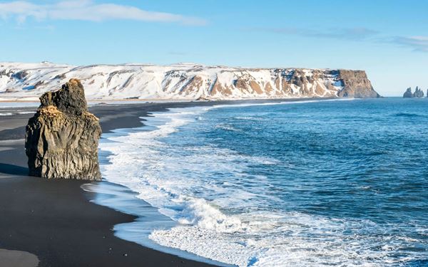 Reynisfjara is world-famous for its dramatic black volcanic sand, massive basalt columns, and the Reynisdrangar sea stacks. The powerful waves of the Atlantic Ocean and the moody, dark atmosphere make it one of the most unique beaches in the world. It is a place of raw natural power and geological wonder, offering a striking contrast between the dark land and the white sea foam.