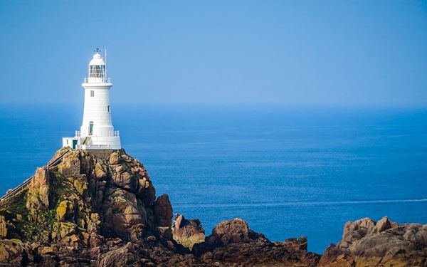 Perched on a rocky islet at the southwestern tip of Jersey, La Corbière is one of the most photographed lighthouses in the world. It is accessible via a causeway at low tide, surrounded by dramatic cliffs and crashing Atlantic waves. The site is famous for its stunning sunsets and its rugged, maritime beauty, symbolizing the island's strong connection to the sea and its wild coastline.