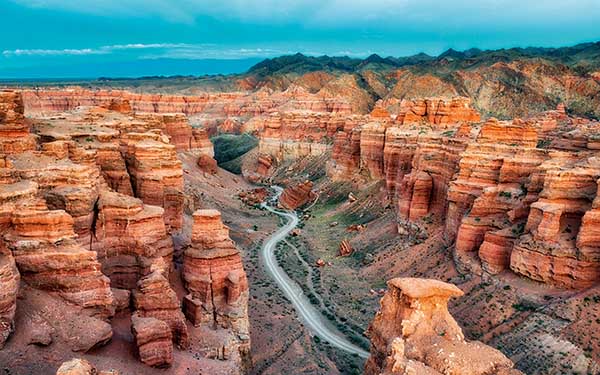 Charyn Canyon is often called the "Little Brother of the Grand Canyon," featuring spectacular red sedimentary rock formations. The "Valley of Castles" is the most popular part, with its tower-like shapes and deep ravines. It offers a dramatic desert landscape in Central Asia, perfect for hiking and photography amidst million-year-old geological history.