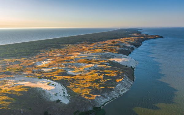 The Curonian Spit is a 98-kilometer long, thin sand dune spit that separates the Curonian Lagoon from the Baltic Sea. This UNESCO site is famous for its massive shifting dunes, pine forests, and the charming fishing village of Nida. It is a place of unique natural beauty and tranquility, where visitors can experience the "Lithuanian Sahara" and a rich, traditional maritime culture.