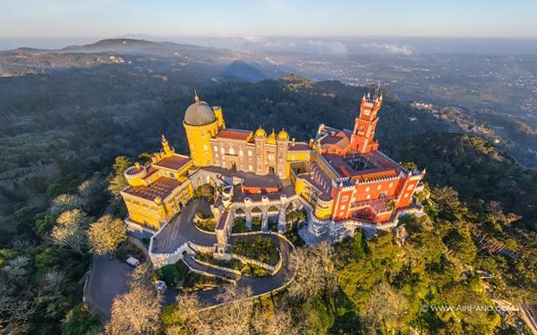 Pena Palace in Sintra is a romanticist masterpiece perched on a hilltop above the town. Famous for its vibrant yellow and red facades, it looks like something out of a fairytale. The palace combines various architectural styles and is surrounded by lush forest and gardens. It is a UNESCO World Heritage site and a crowning jewel of 19th-century Portuguese architecture and culture.