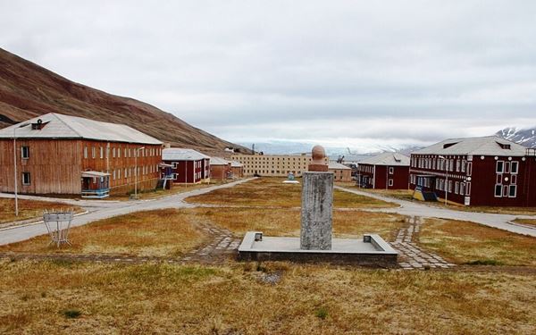 Pyramiden is a former Soviet coal-mining settlement that was abandoned in 1998, leaving behind a "ghost town" frozen in time. Visitors can explore the preserved residential blocks, the northernmost statue of Lenin, and the cultural palace. Surrounded by glaciers and mountains, it offers a hauntingly beautiful and nostalgic look at the Cold War era and the industrial history of the Arctic in a surreal setting.