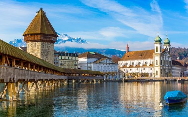 The Chapel Bridge (Kapellbrücke) is a historic wooden covered bridge in Lucerne, famous for its interior paintings and octagonal water tower. As one of the oldest wooden bridges in Europe, it is the center of the city's picturesque landscape. Walking across the bridge offers a romantic view of the Reuss River and the surrounding medieval architecture and mountain peaks.