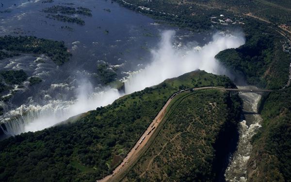 Victoria Falls, or "The Smoke that Thunders," is one of the Seven Natural Wonders of the World. On the Zambian side, visitors can walk across the Knife-Edge Bridge for a face-to-face view of the massive curtain of water. During the dry season, the daring "Devil's Pool" allows for a swim at the very edge of the falls. It is a majestic and awe-inspiring display of nature's power, marking the border between Zambia and Zimbabwe.